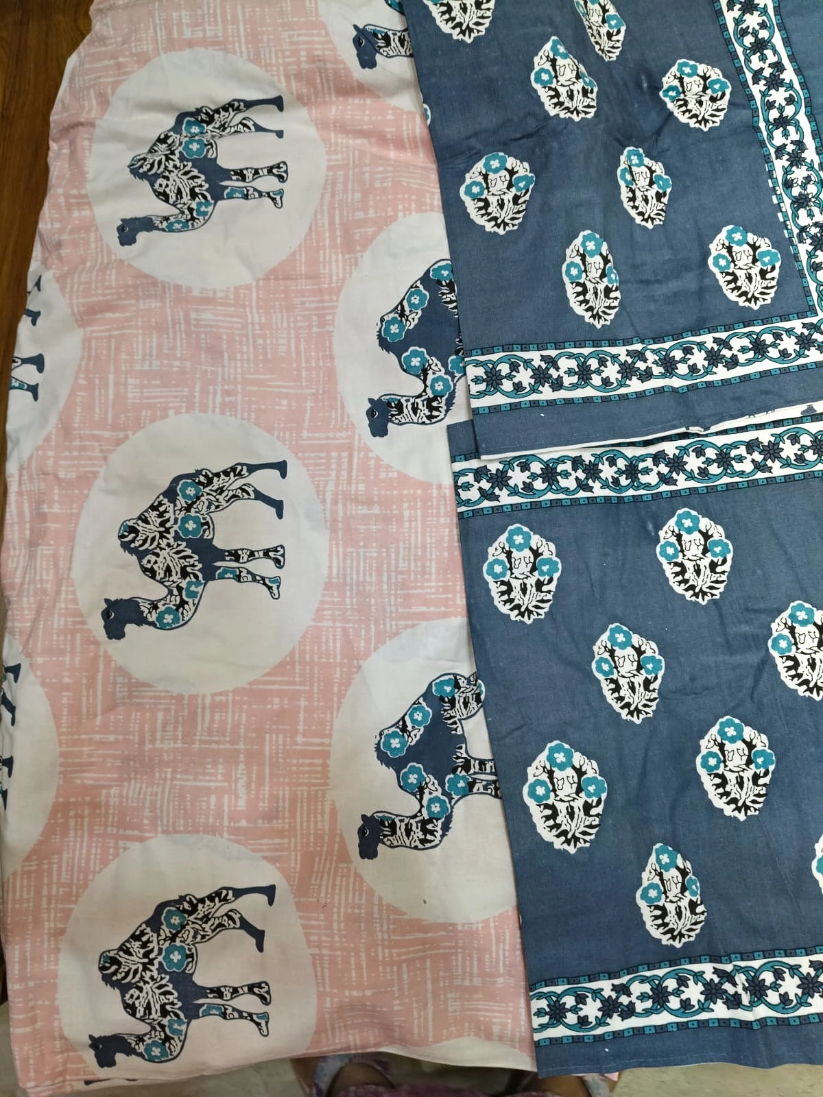 The Camels: camels in cream roundels on blush pink, with blue paisley pillowcases, folded.