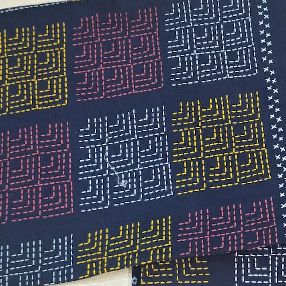 Close-up of The Dancers, navy: dancing figures and square panels in ochre, rose and white on navy cotton.
