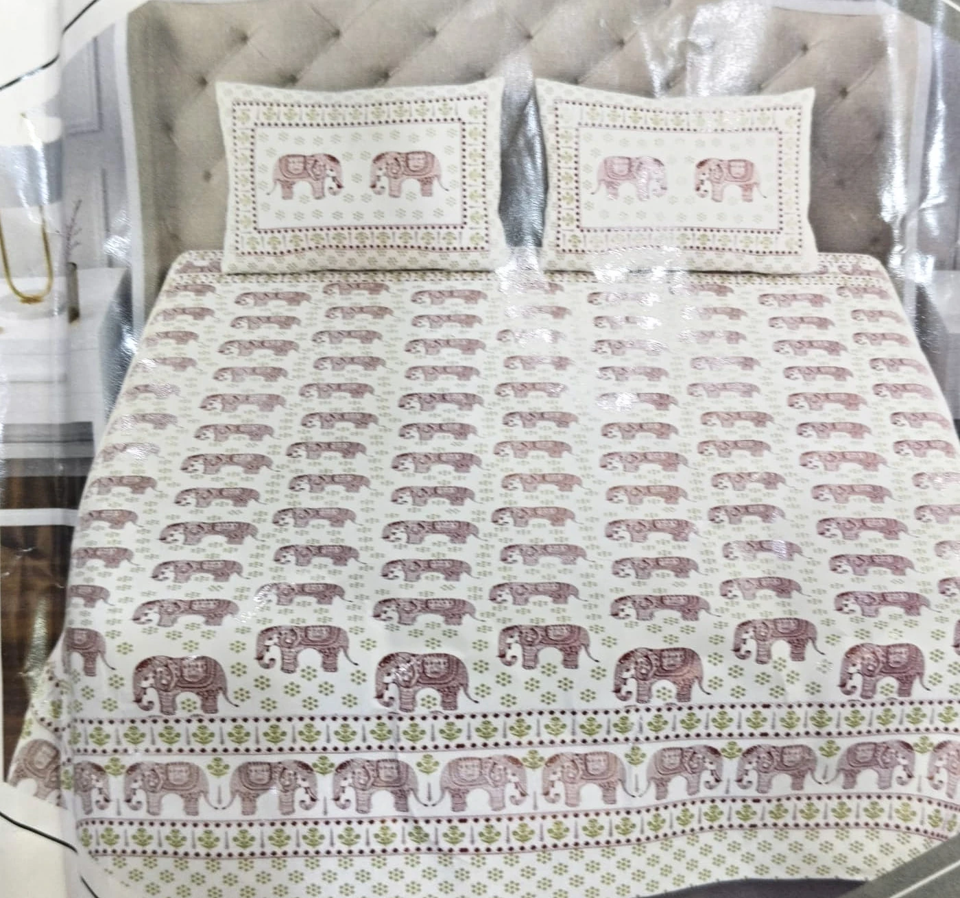 The Elephant Parade: rows of small elephants in rose and grey on white, with elephant-panel pillowcases, on a made bed with matching pillowcases.