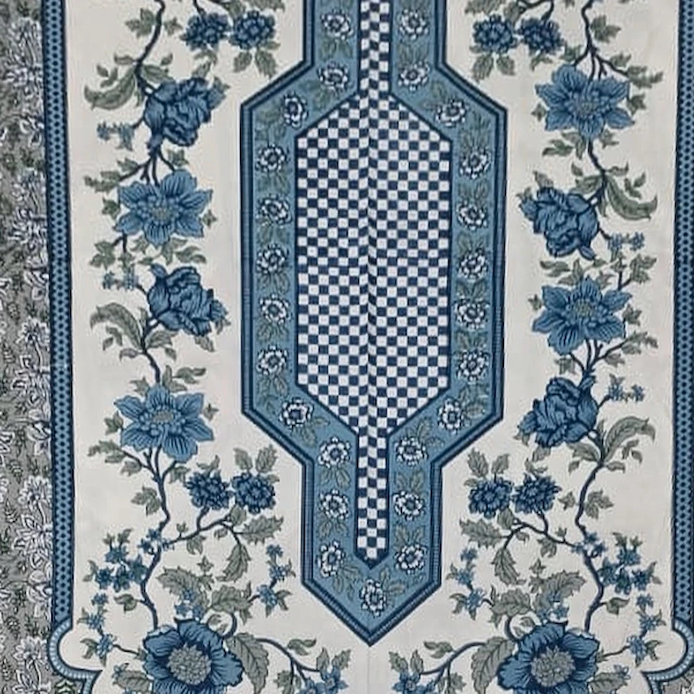 Close-up of The Fernleaf: blue-grey floral cloth with a long ivory centre panel and two matching pillowcases.