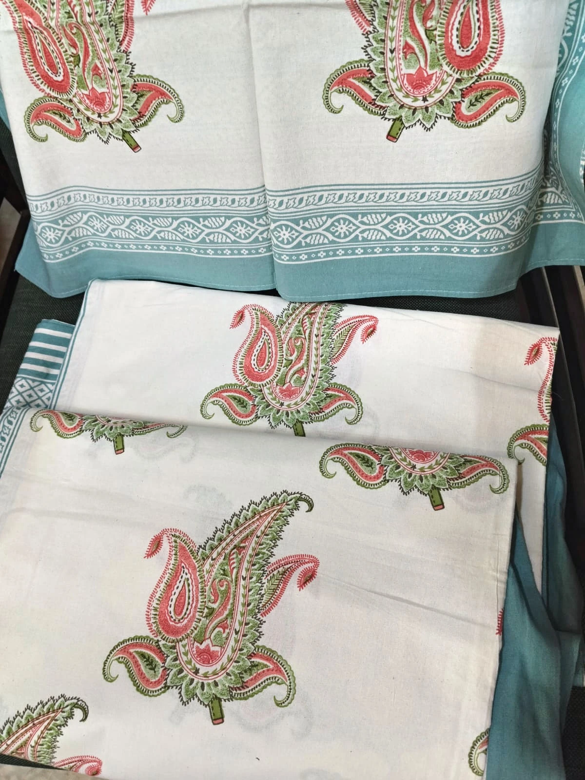 The Paisley, white: rose and green paisley on white cotton with a teal border, folded.