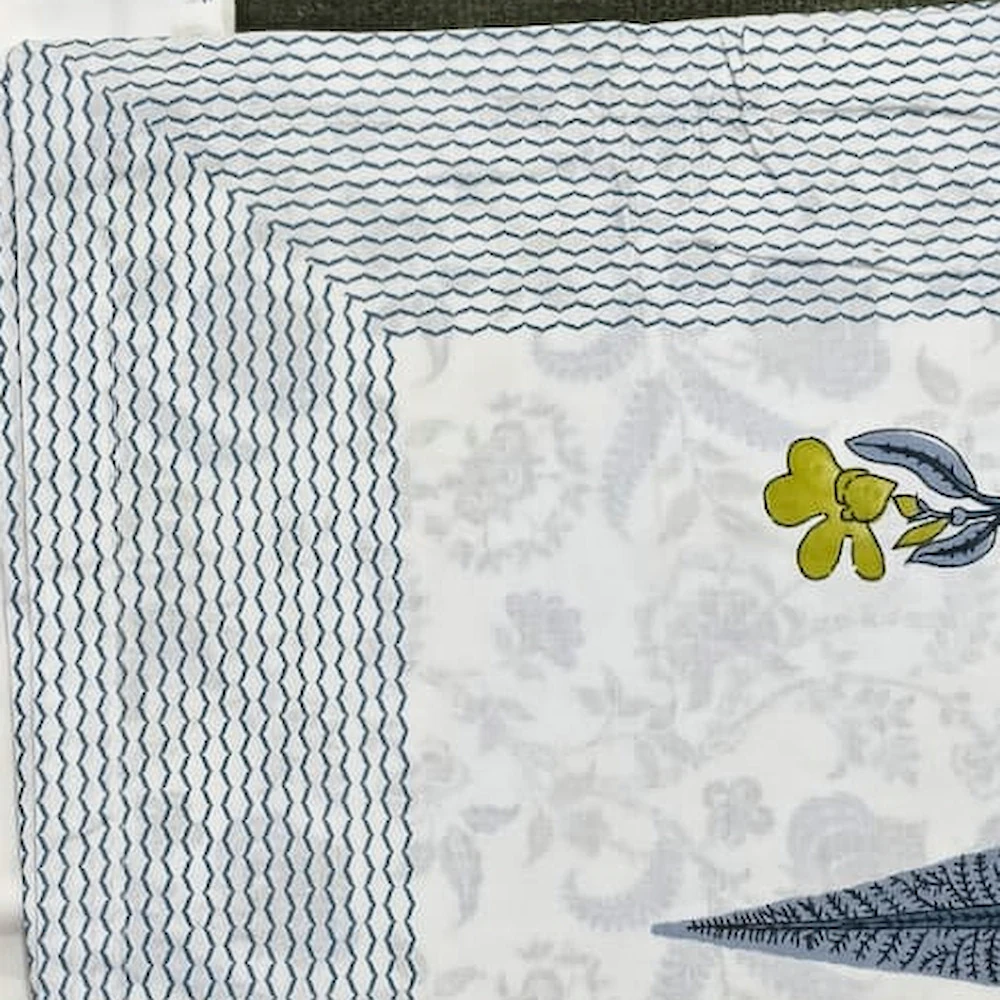 Close-up of The Wildflower: scattered blue leaves and small yellow flowers on white with a grey border.