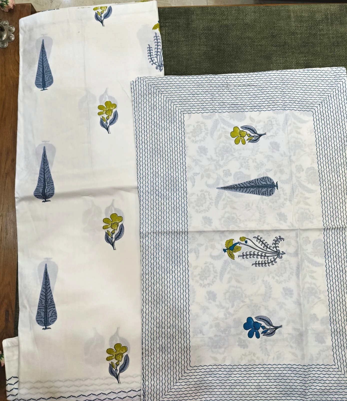 The Wildflower: scattered blue leaves and small yellow flowers on white with a grey border, folded.